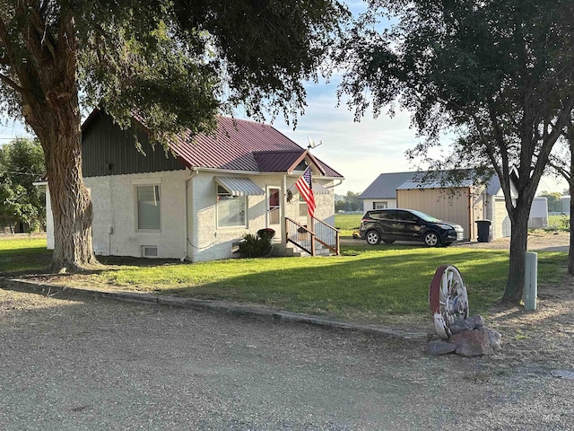 view of front of house with metal roof, a front lawn, and stucco siding