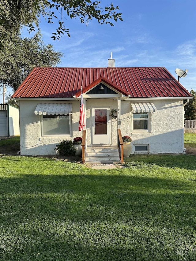 view of front of home featuring a front lawn, metal roof, and stucco siding