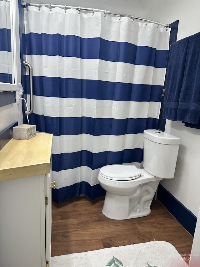 full bath featuring toilet, a shower with shower curtain, wood finished floors, vanity, and baseboards