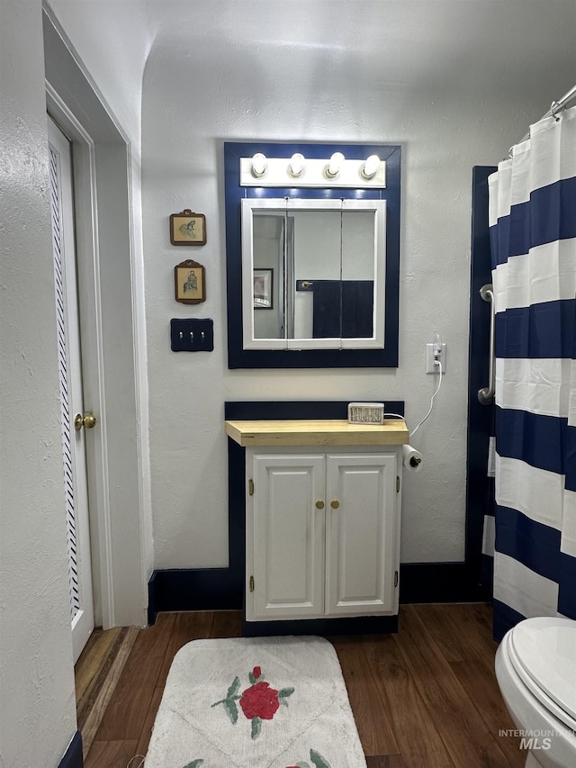 bathroom featuring baseboards, vanity, toilet, and wood finished floors