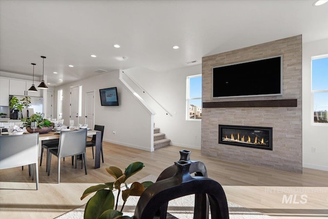 living area with stairway, recessed lighting, a large fireplace, and light wood-style floors