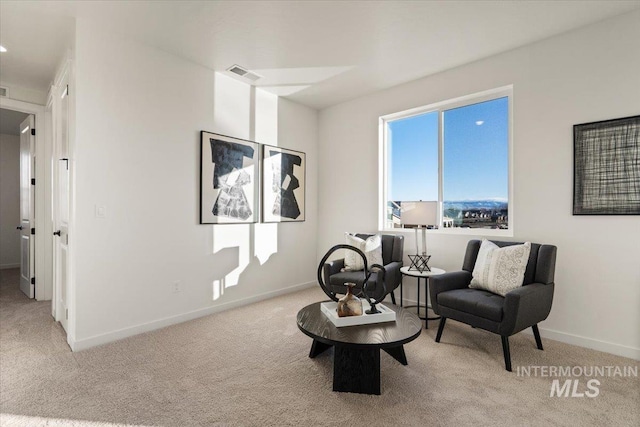 living area featuring baseboards, visible vents, and light carpet