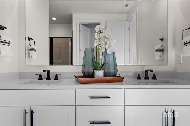 full bath featuring a shower stall, double vanity, and a sink