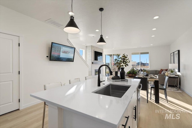 kitchen featuring light countertops, light wood-style flooring, visible vents, and a sink