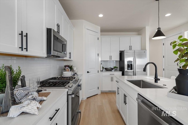 kitchen featuring light countertops, decorative light fixtures, appliances with stainless steel finishes, and a sink