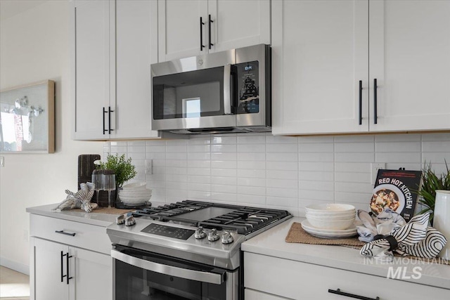 kitchen with tasteful backsplash, white cabinetry, stainless steel appliances, and light countertops