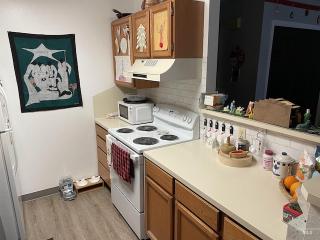 kitchen featuring tasteful backsplash, white appliances, and light wood-type flooring