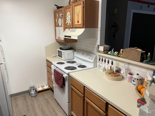 kitchen featuring white appliances, light hardwood / wood-style floors, and decorative backsplash