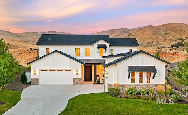 modern farmhouse style home with a mountain view, a garage, and a lawn