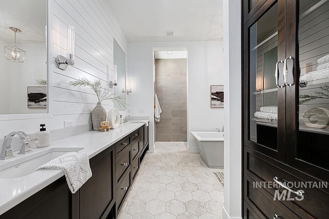 bathroom featuring double vanity, tile walls, a tub, and tile patterned floors