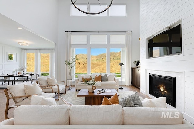 living room with a fireplace, a towering ceiling, light hardwood / wood-style flooring, and a wealth of natural light