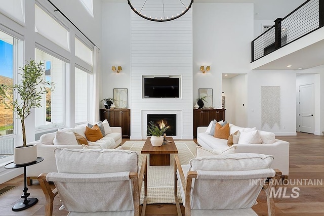 living room with a fireplace, wood-type flooring, a high ceiling, and plenty of natural light