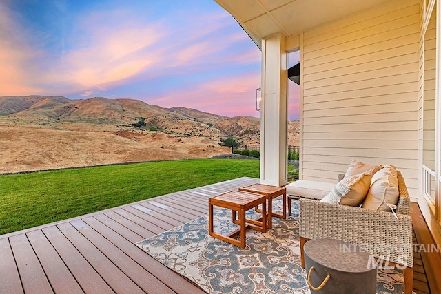 deck at dusk with a mountain view and a yard