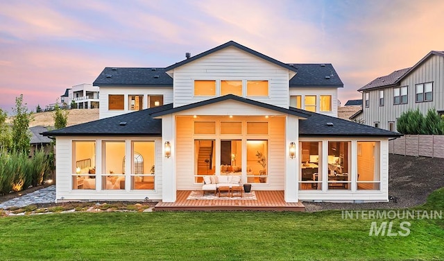 back house at dusk featuring a lawn