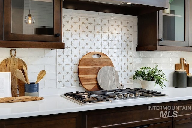 kitchen with stainless steel gas stovetop, dark brown cabinets, backsplash, and decorative light fixtures