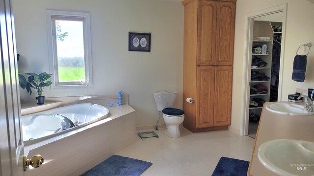 bathroom featuring double sink, a bathtub, and toilet