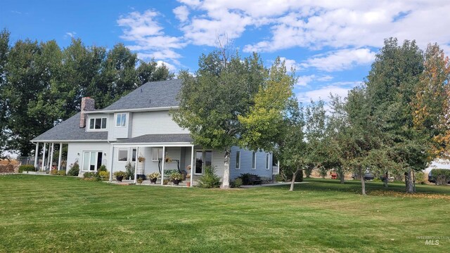 rear view of house with a lawn and a porch