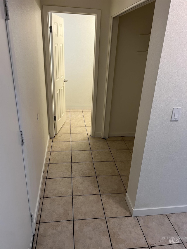 corridor featuring light tile patterned flooring and baseboards