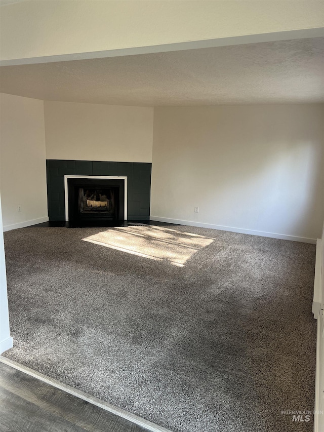 unfurnished living room with baseboards, a fireplace, and carpet