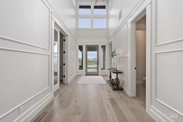 entryway with light hardwood / wood-style floors and a towering ceiling