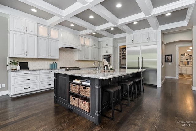 kitchen with a large island with sink, white cabinets, appliances with stainless steel finishes, and a kitchen breakfast bar