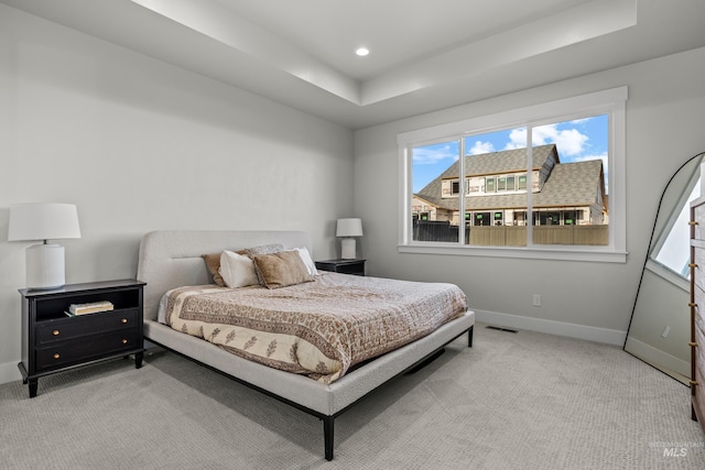 carpeted bedroom featuring a raised ceiling and multiple windows