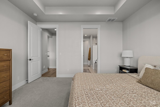 carpeted bedroom featuring connected bathroom and a raised ceiling