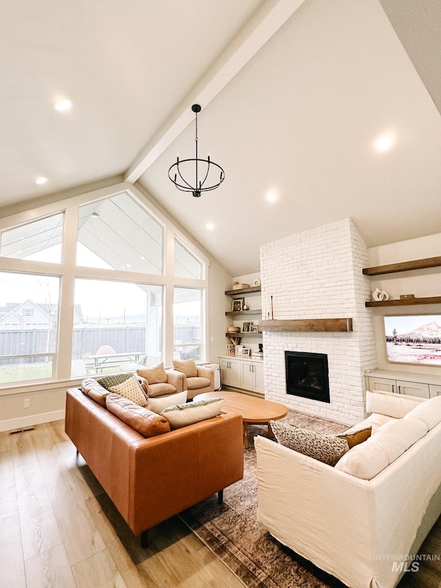 living room featuring high vaulted ceiling, an inviting chandelier, light hardwood / wood-style flooring, a fireplace, and beam ceiling