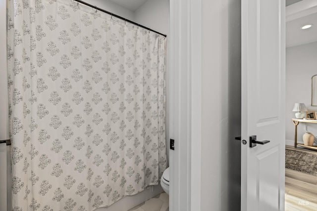 bathroom with hardwood / wood-style flooring, toilet, and curtained shower