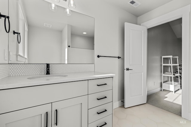 bathroom featuring tile patterned flooring, vanity, and tasteful backsplash