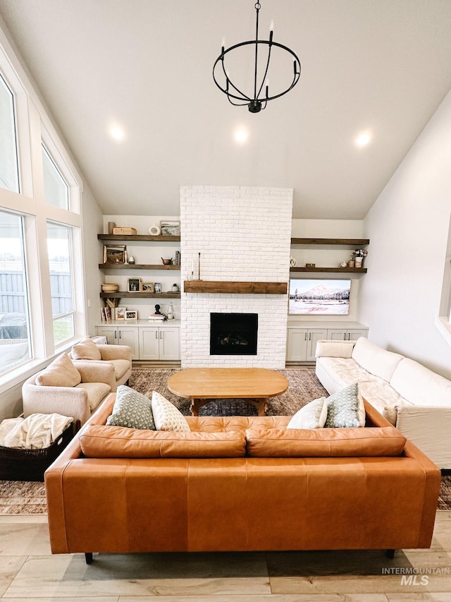 living room with a fireplace, high vaulted ceiling, and a notable chandelier