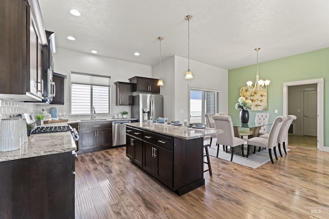 18277 N Streams Edge Way, Boise, ID 83714 - kitchen with appliances with stainless steel finishes, dark brown cabinetry, wood finished floors, a sink, and a chandelier