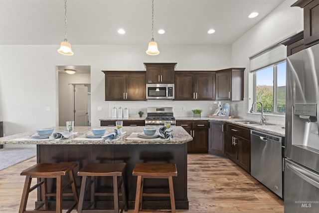 18277 N Streams Edge Way, Boise, ID 83714 - kitchen featuring appliances with stainless steel finishes, a sink, wood finished floors, a kitchen bar, and recessed lighting