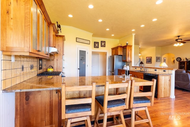 kitchen featuring stainless steel appliances, sink, light wood-type flooring, and kitchen peninsula