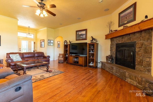 living room featuring crown molding, ceiling fan, wood-type flooring, and a fireplace