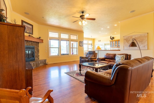 living room with crown molding, hardwood / wood-style floors, a textured ceiling, and a fireplace