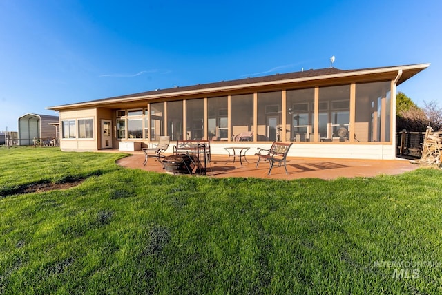 rear view of house with a patio, a sunroom, a yard, and a fire pit