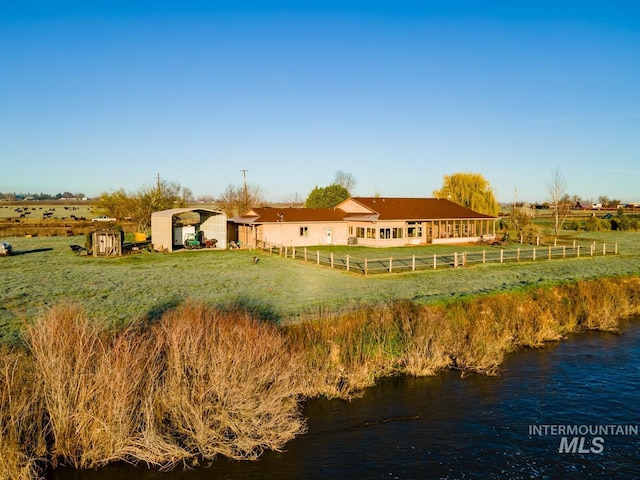 rear view of property featuring a water view, a lawn, and a rural view