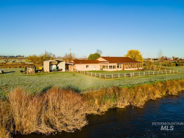 rear view of house featuring a rural view, a yard, and a water view