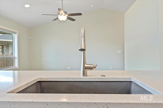 interior details with a ceiling fan, a sink, and light stone countertops
