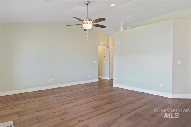 spare room with baseboards, wood finished floors, arched walkways, and ceiling fan