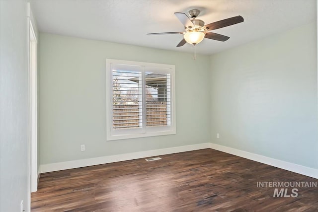 unfurnished room featuring baseboards, ceiling fan, visible vents, and dark wood-type flooring