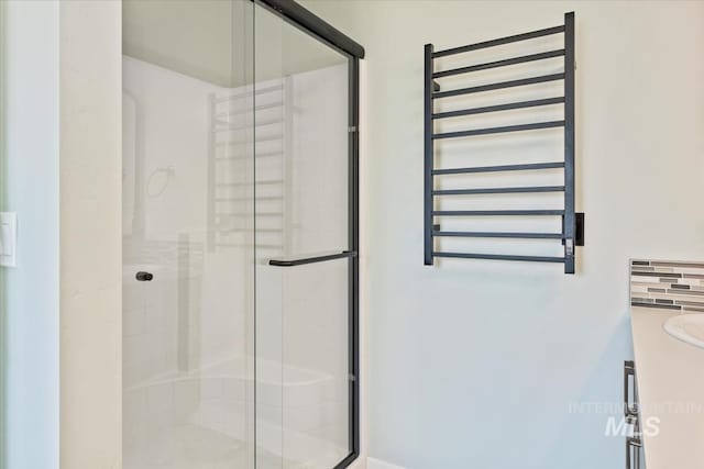 bathroom with a shower stall, radiator heating unit, and vanity