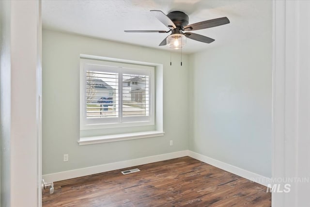 empty room with baseboards, dark wood-style flooring, ceiling fan, and visible vents
