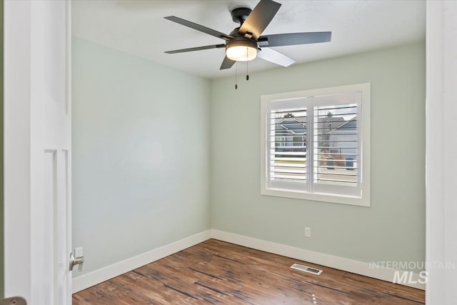 spare room with baseboards, visible vents, wood finished floors, and ceiling fan