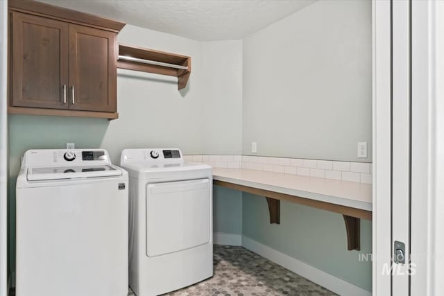 clothes washing area featuring a textured ceiling, cabinet space, and washing machine and dryer