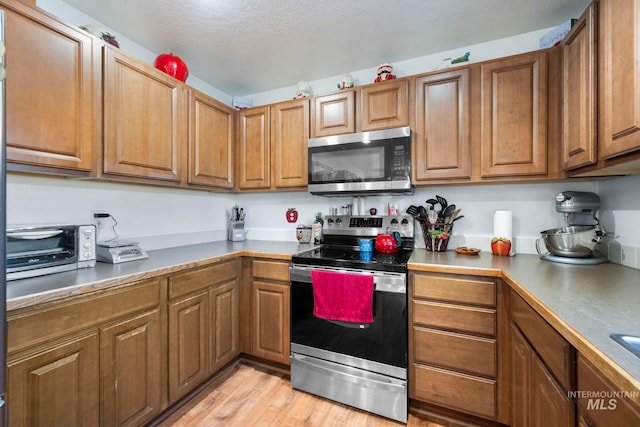1056 S Hebgon Lake Ave, Middleton, ID 83644 - kitchen featuring stainless steel appliances, brown cabinets, and light wood finished floors
