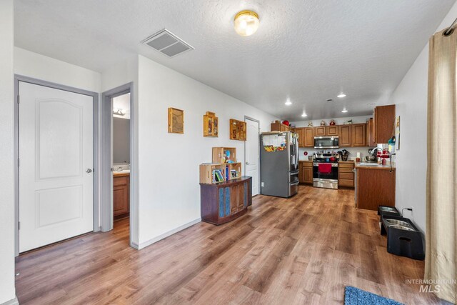 1056 S Hebgon Lake Ave, Middleton, ID 83644 - kitchen featuring appliances with stainless steel finishes, brown cabinetry, light wood-style floors, light countertops, and recessed lighting