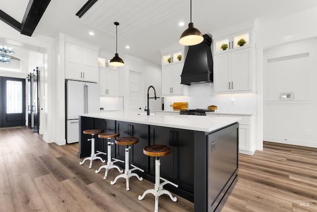 11127 Lake Lowell Ave, Nampa, ID 83686 - kitchen featuring premium range hood, freestanding refrigerator, tasteful backsplash, wood finished floors, and an island with sink