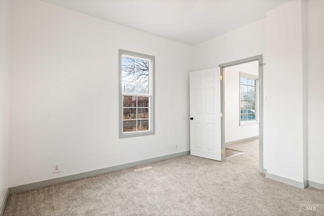 carpeted spare room featuring baseboards and a healthy amount of sunlight